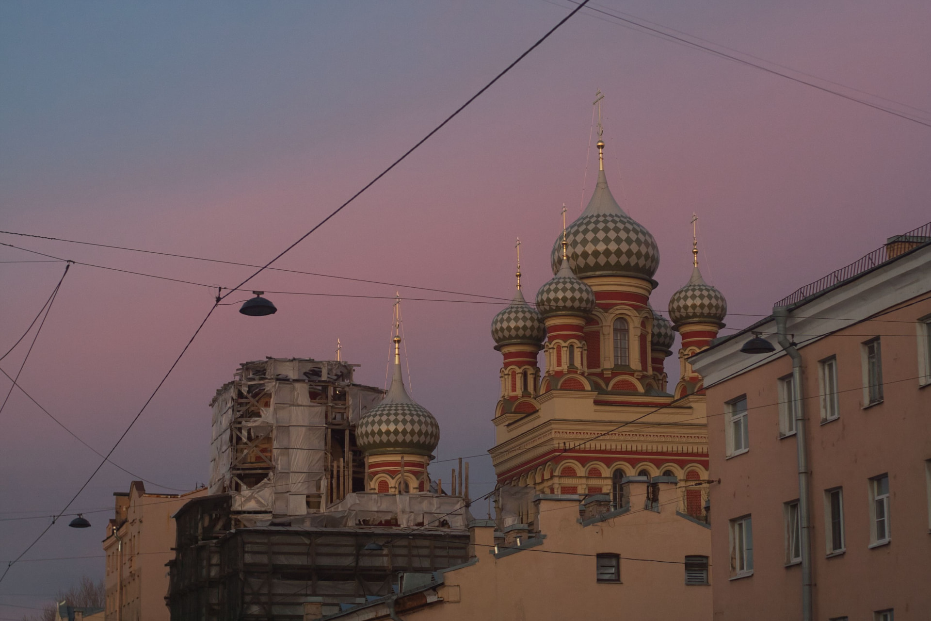 Russian Orthodox church domes above an urban street at dusk.